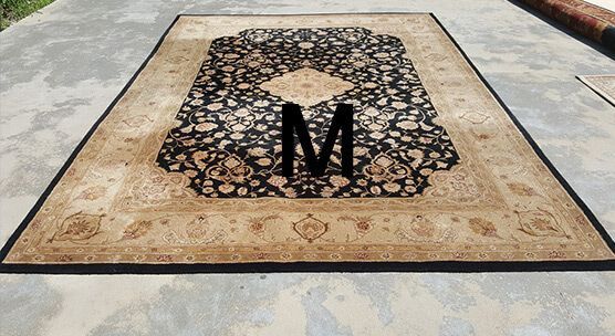A rug with the letter m on it is sitting on the ground.