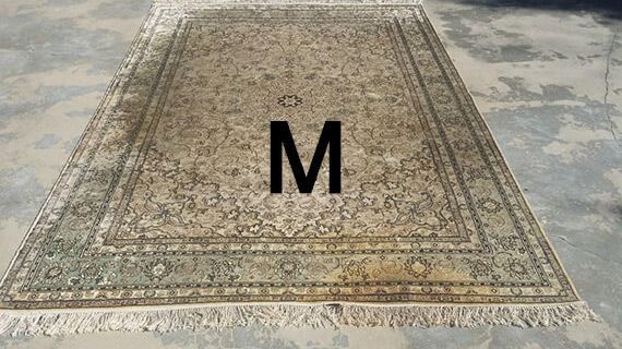 A rug with the letter m on it is sitting on the ground.