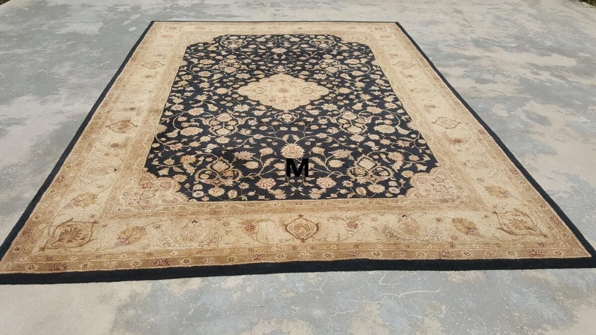 A rug with a black border is sitting on a concrete floor.