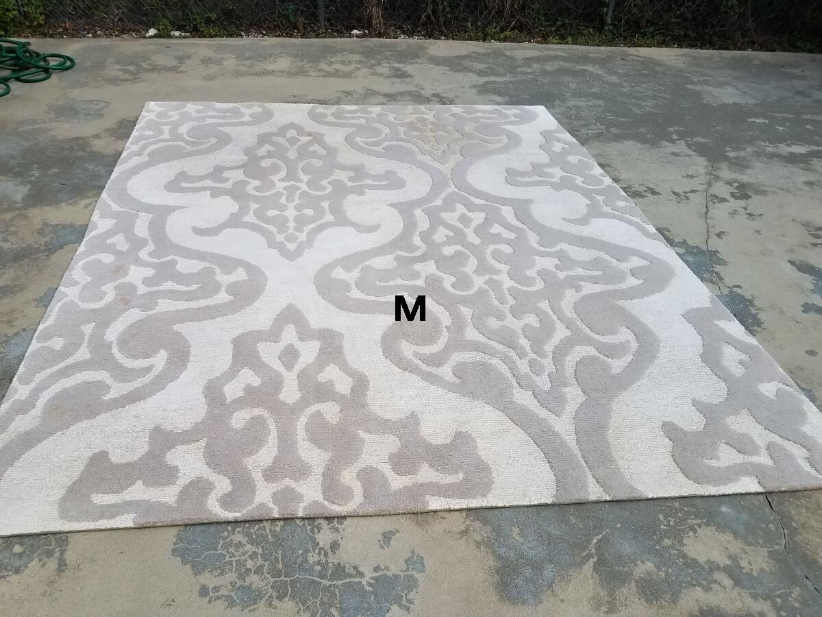 A white rug with a pattern on it is sitting on the ground.