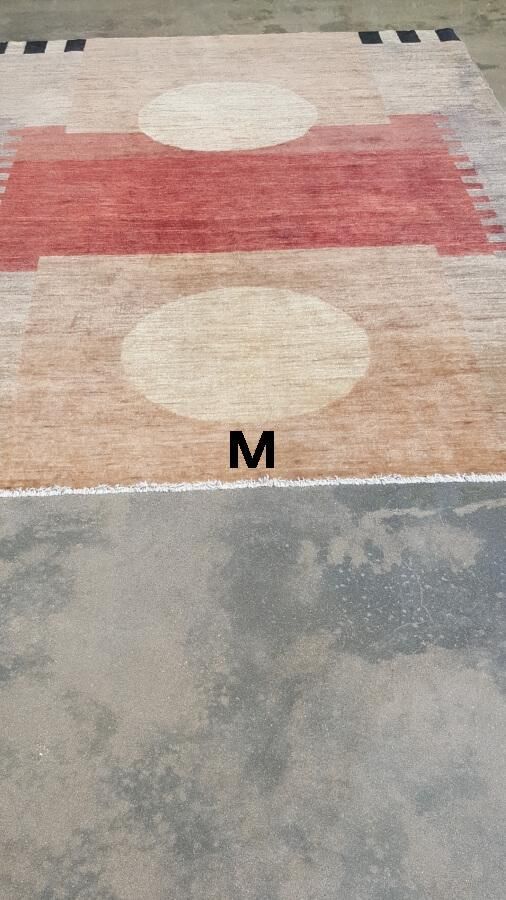 A rug with the letter m on it is on a concrete floor.