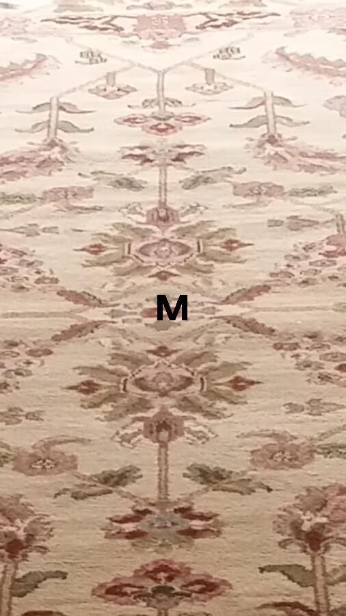 A rug with a floral pattern and the letter m on it.