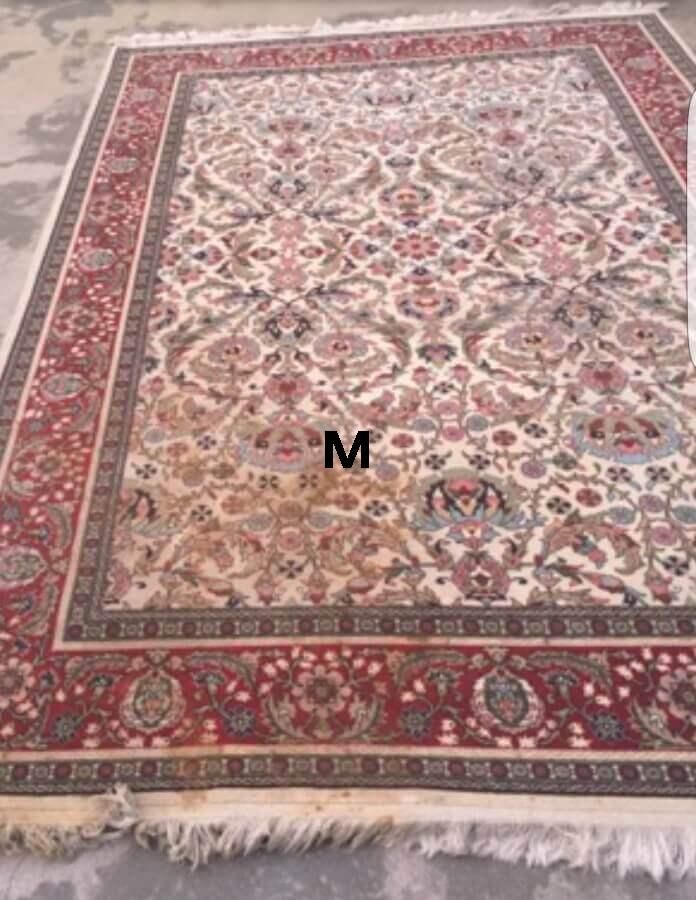 A rug with a pattern on it is sitting on a concrete floor.