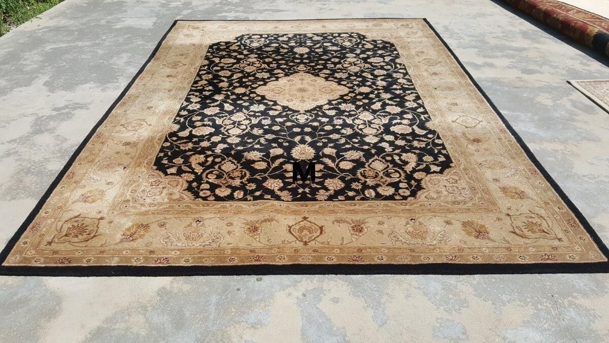 A rug with a black border is sitting on a concrete surface.