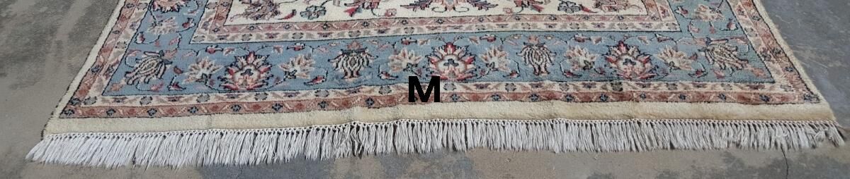 A rug with fringe is sitting on a wooden floor.