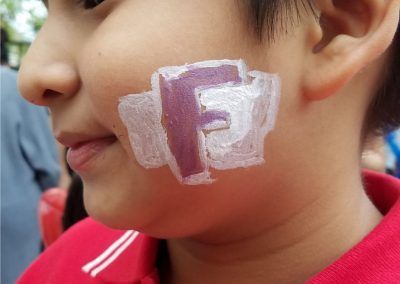 A child with a painted purple letter 