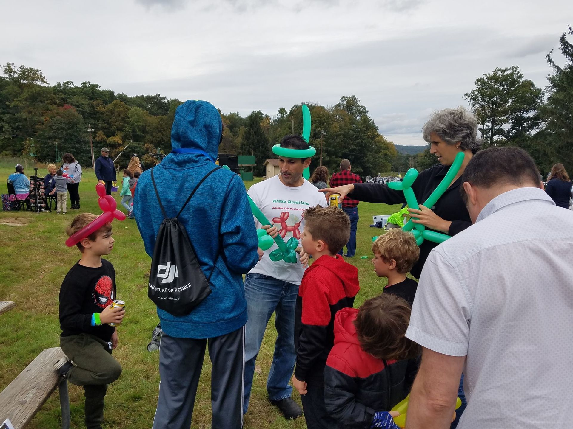 A man making balloon animals for children in a park.