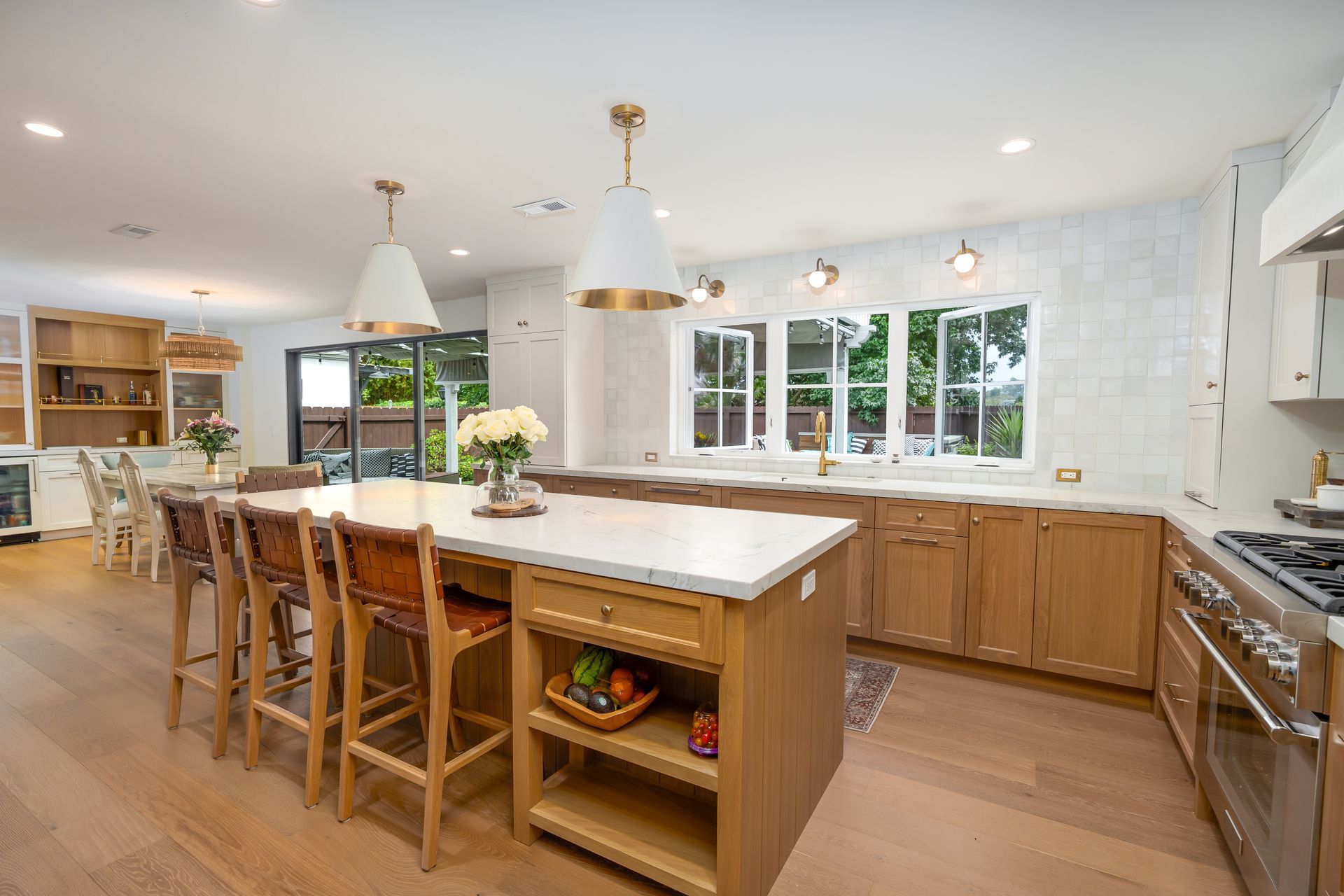 Spacious, bright kitchen with light wood cabinets, white countertops, and large island with seating.