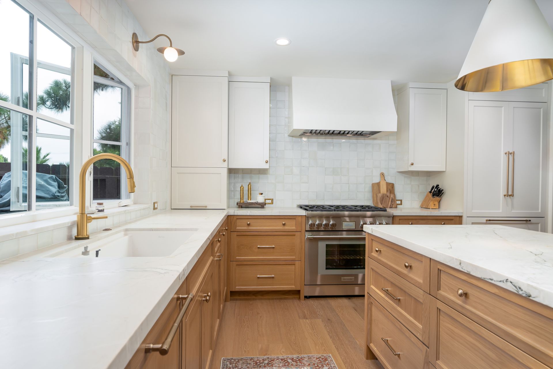 Modern kitchen with white and light wood cabinets, gold accents, and island.