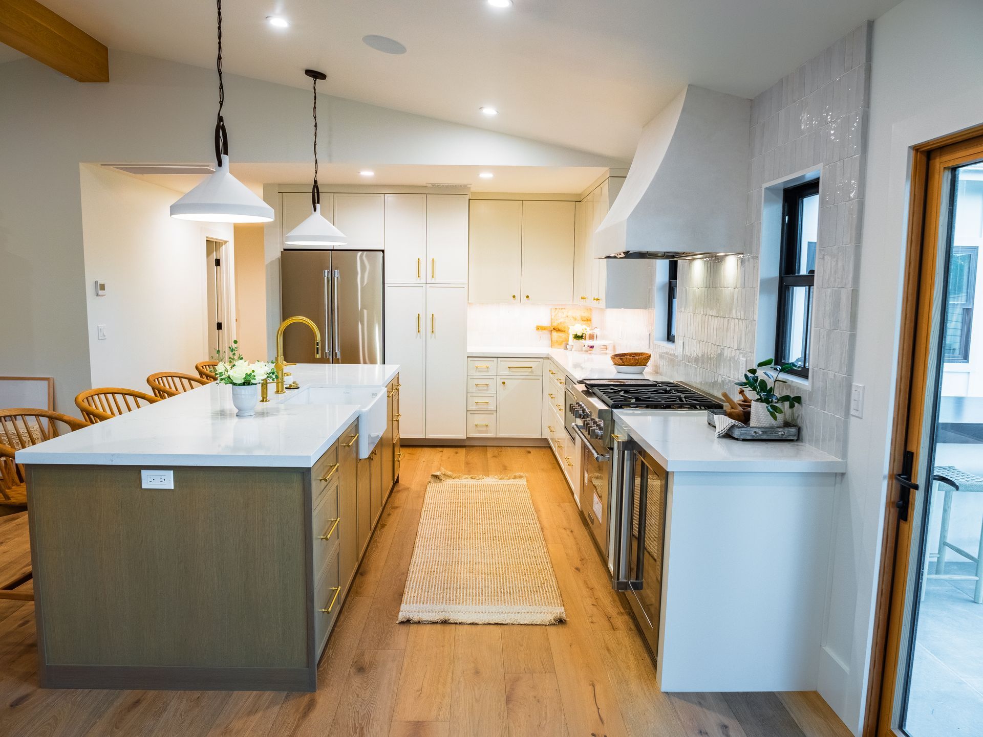Modern kitchen with island, white countertops, stainless appliances, wood floors, and cream cabinets.