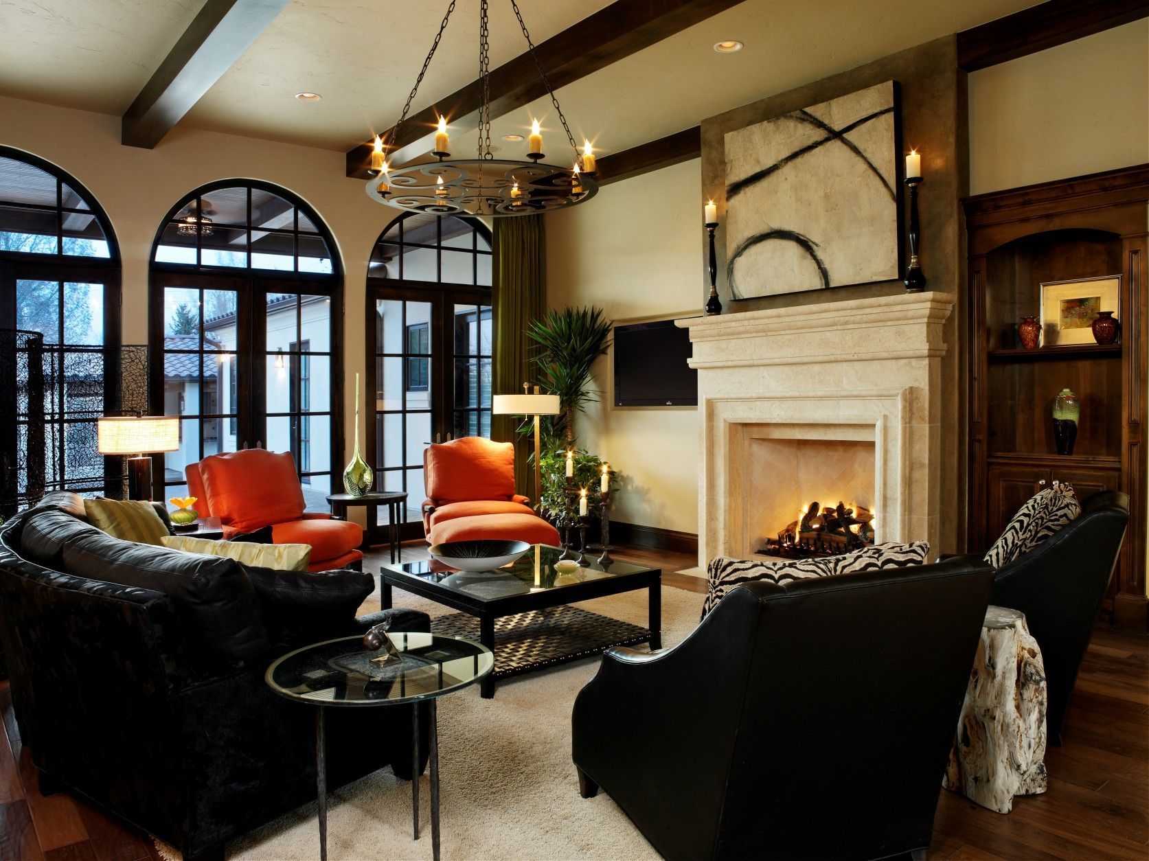 Living room with black leather furniture, orange chairs, fireplace, and arched windows.
