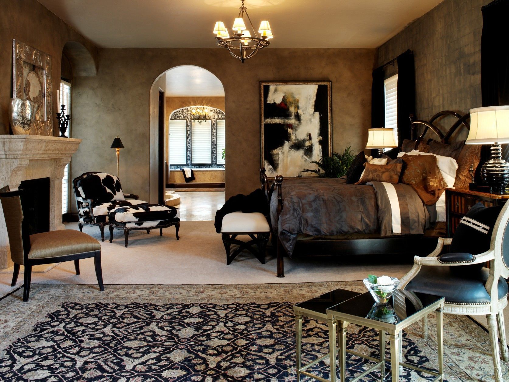 Elegant bedroom with fireplace, ornate rug, and bed with dark brown bedding.