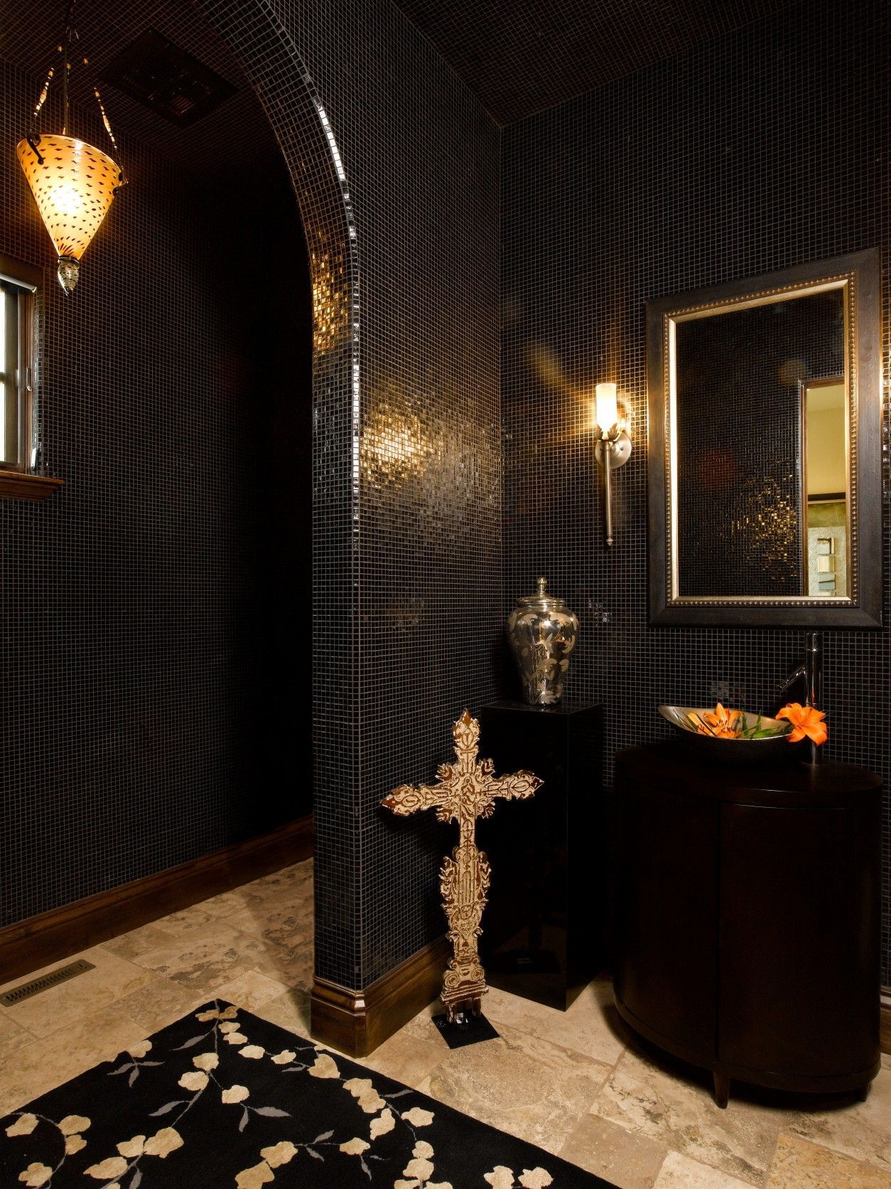 Elegant, dark-themed hallway with patterned black walls, decorative cross, sconce lighting, and a floral rug.
