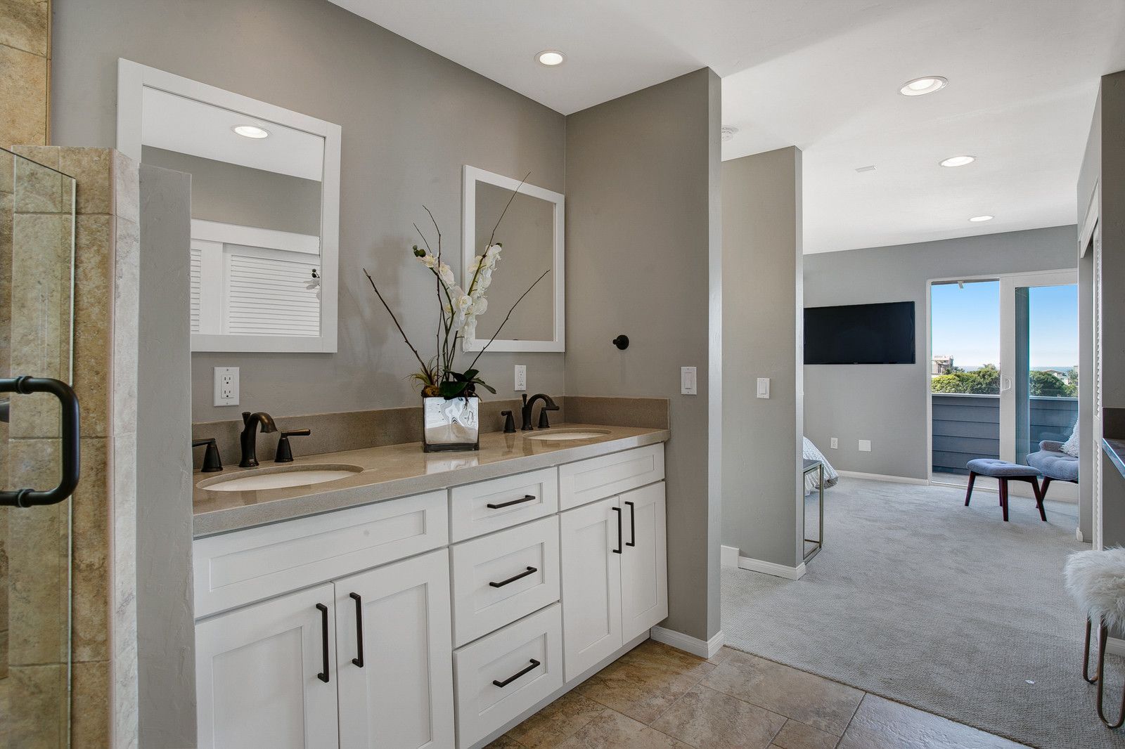 Bathroom with white vanity, gray walls, and a hallway leading to a bedroom with balcony access.