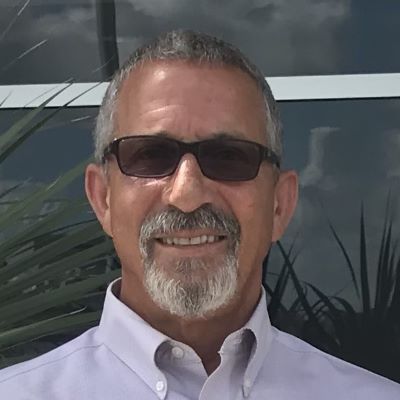 A man wearing glasses is sitting in front of a laptop computer.