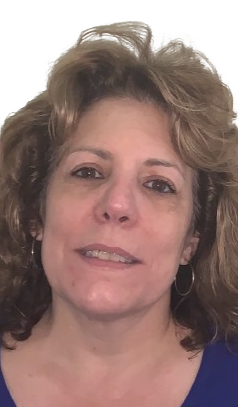 A woman wearing glasses and a white shirt is smiling for the camera.