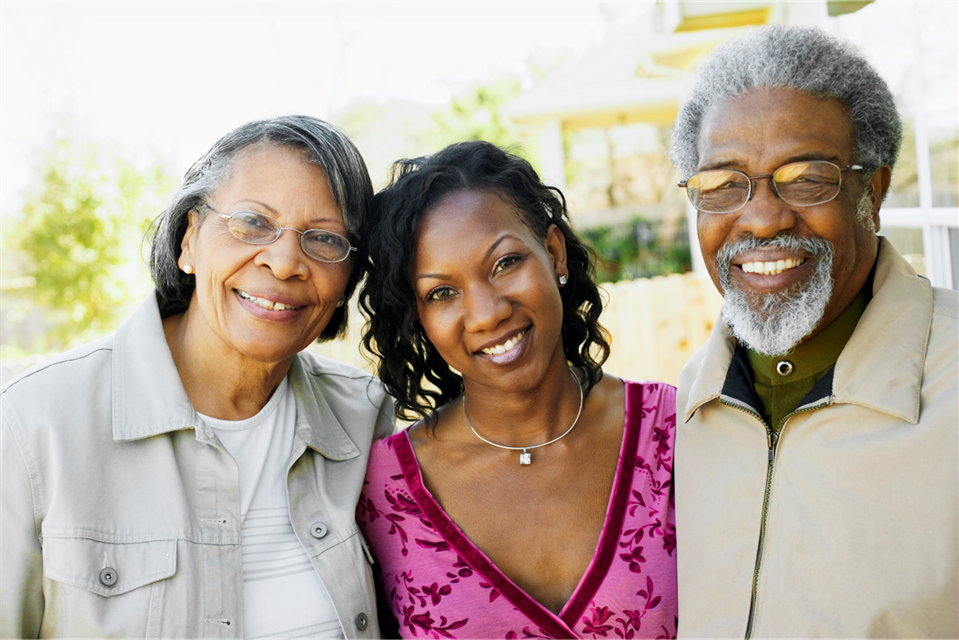Woman with her parents, smiling outdoors.