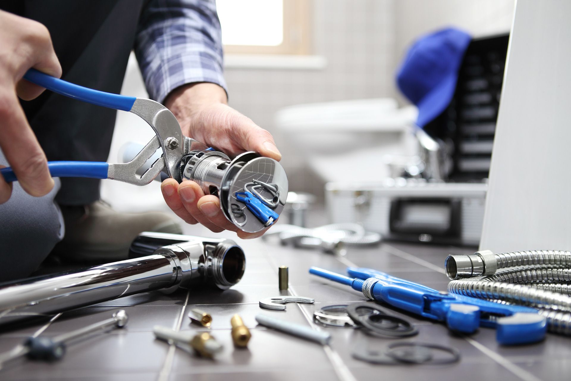 A plumber is fixing a pipe with a wrench in a bathroom.