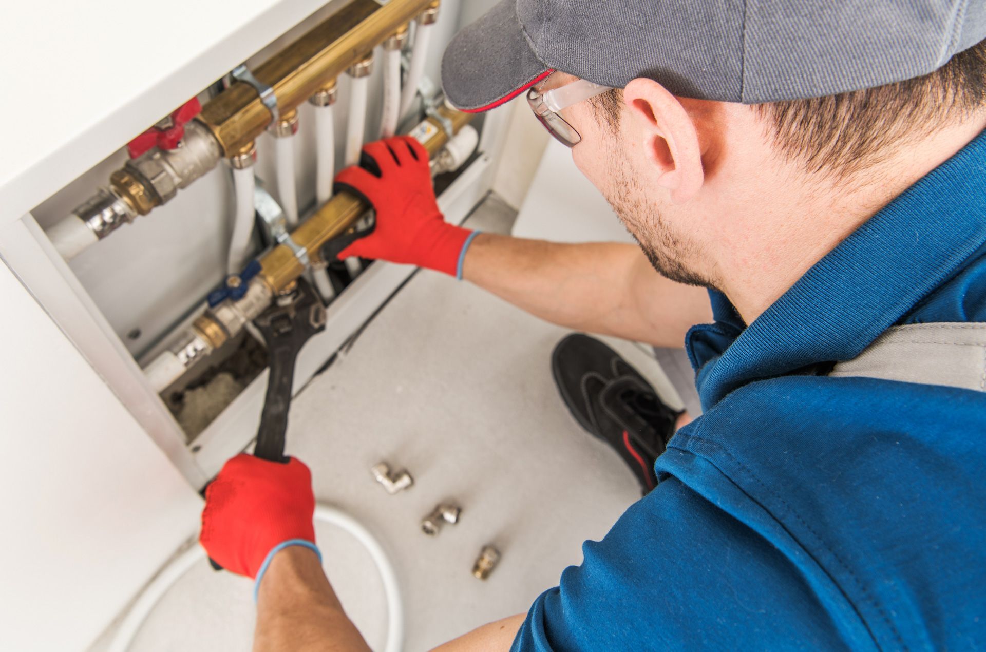 A man is fixing a pipe with a wrench.