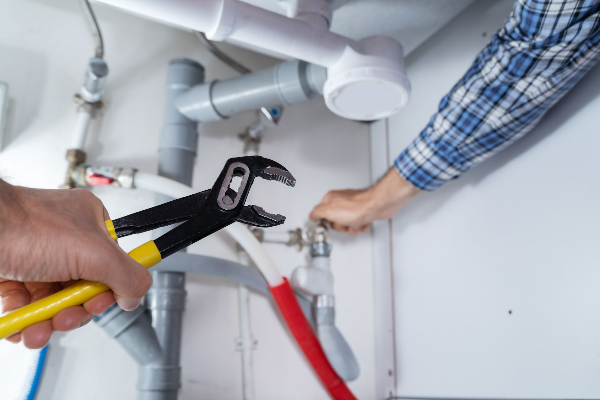 A plumber is fixing a sink with a wrench.