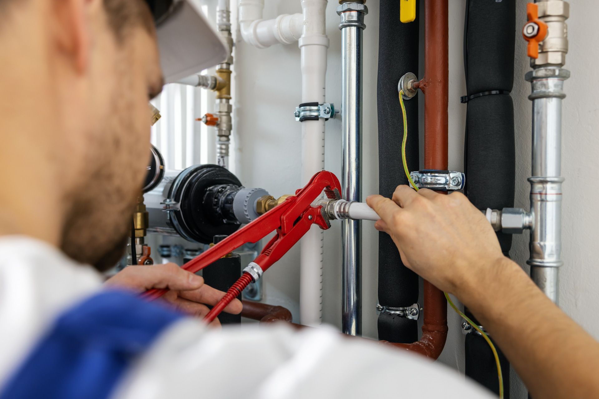 A plumber is working on a pipe with a wrench.