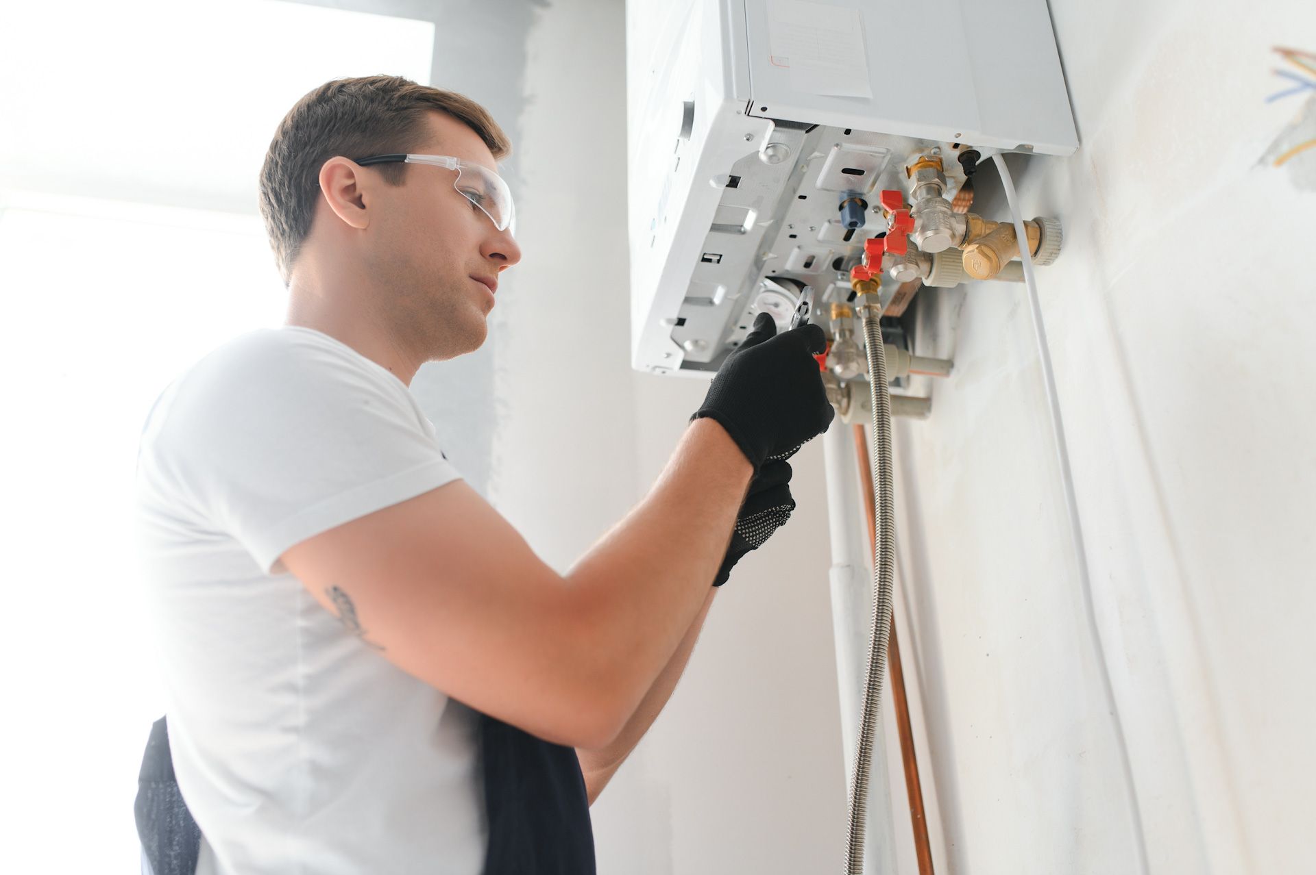 A man is fixing a water heater on the wall.