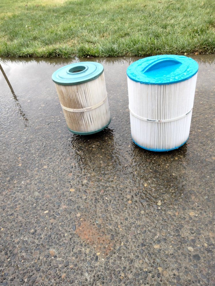 Two pool filters are sitting on the sidewalk next to each other.