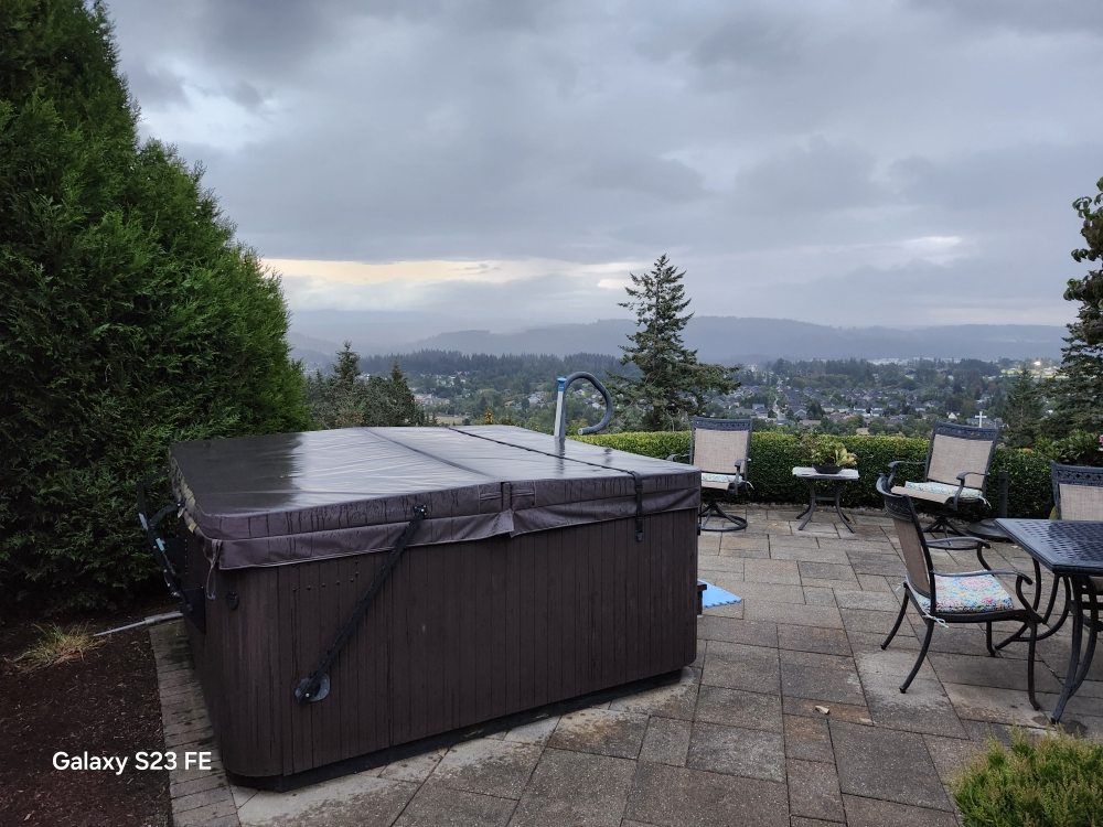 A hot tub is sitting on a patio next to a table and chairs.