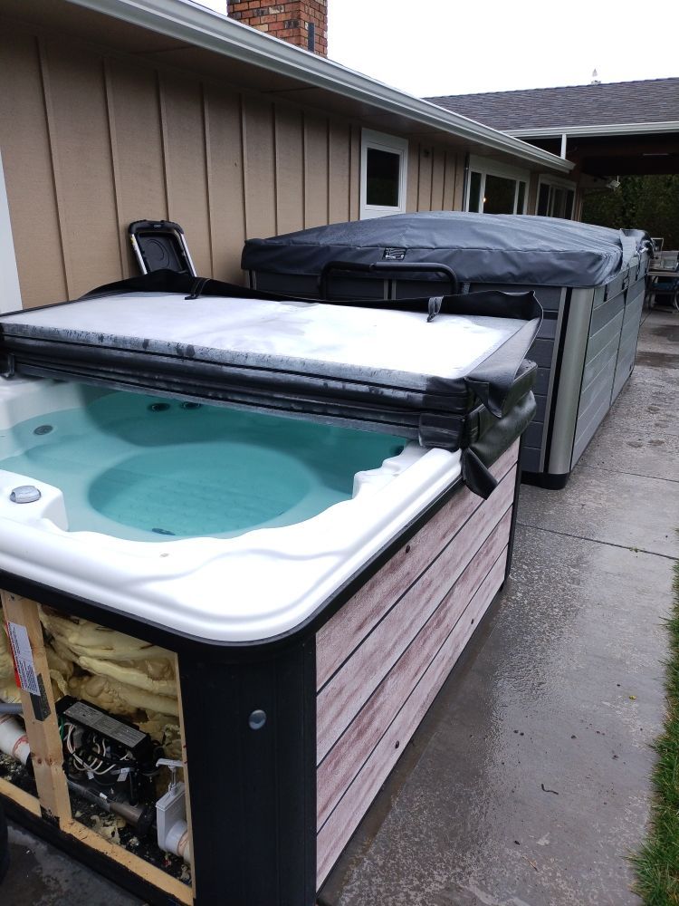 A hot tub is sitting on the sidewalk in front of a house.