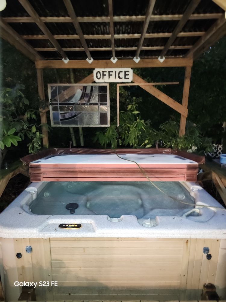 A hot tub is under a wooden structure with a sign that says office.