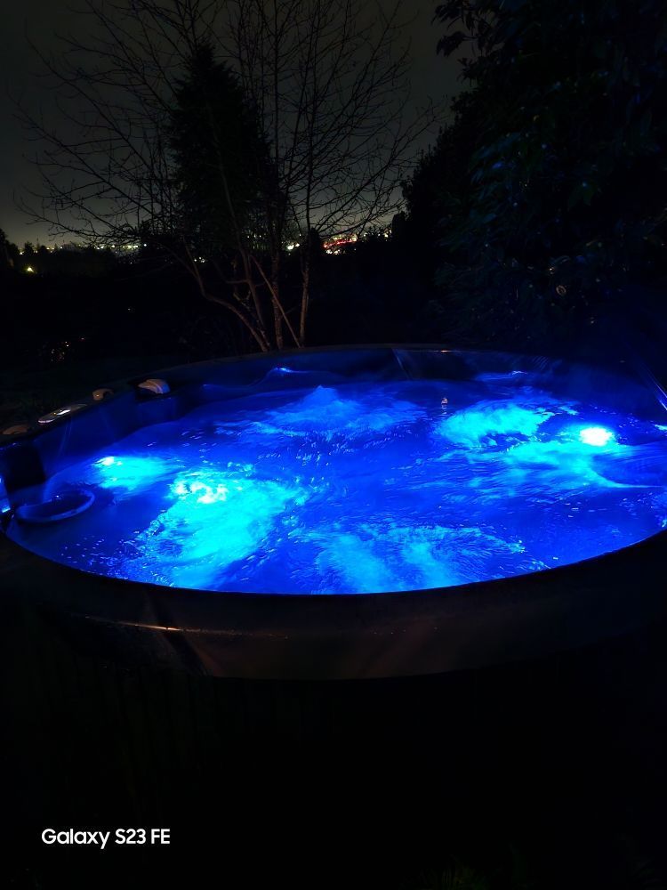 A hot tub is lit up with blue lights at night.