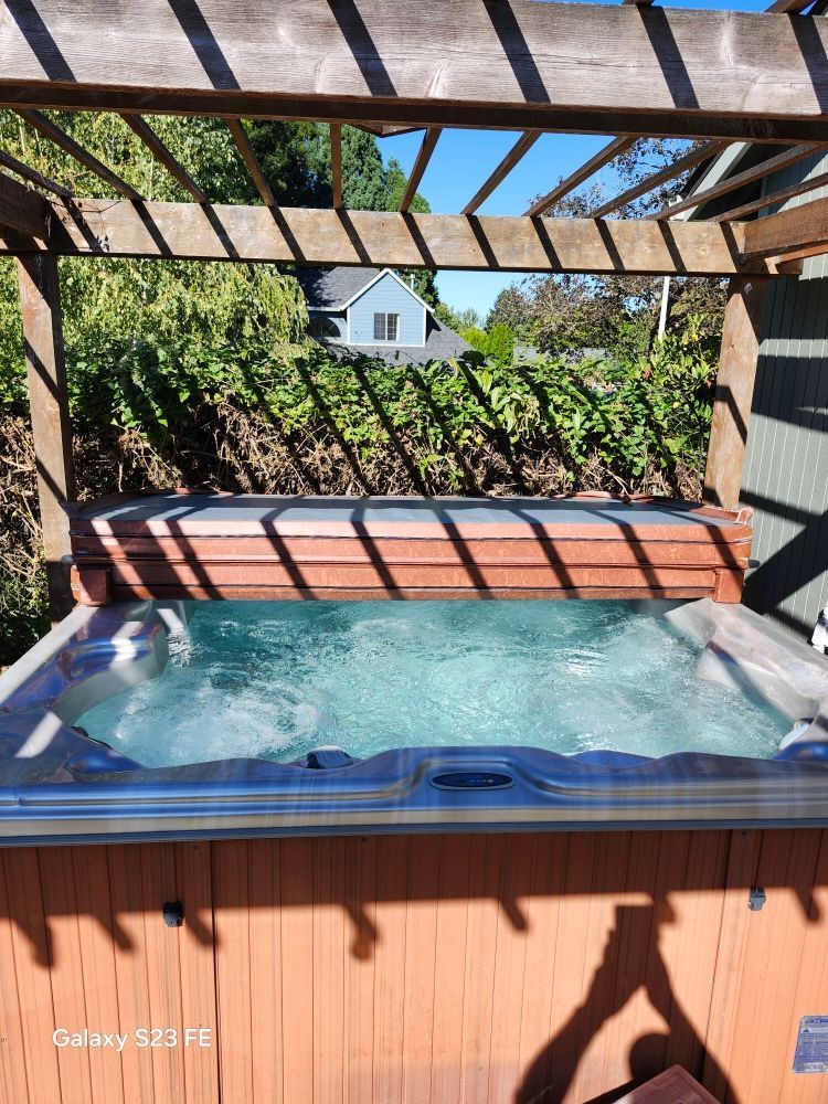 A hot tub is sitting under a wooden pergola.