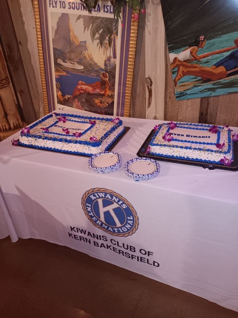 A table with two cakes and a sign that says Kiwanis club
