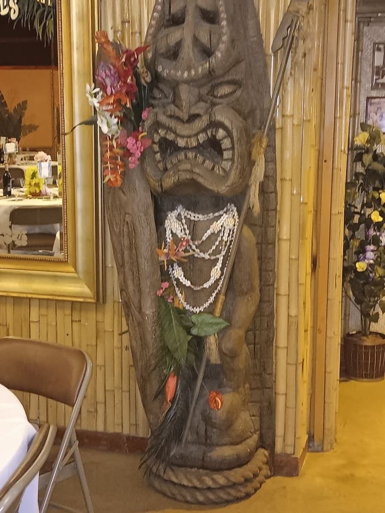 A statue of a tiki with flowers and pearls on it