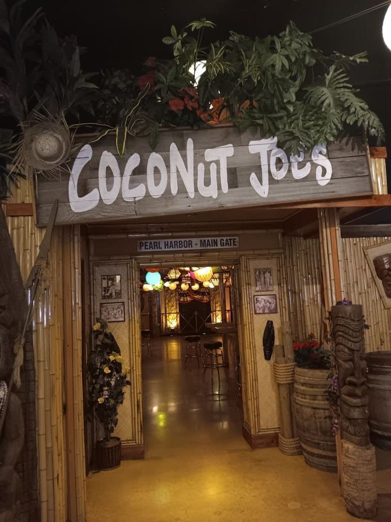 The entrance to the coconut joes restaurant is decorated with tiki statues.