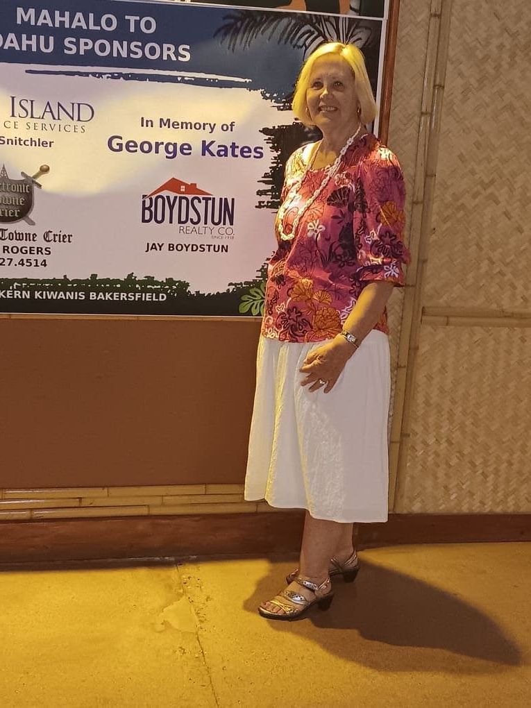 A woman stands in front of a sign that says mahalo to ahu sponsors