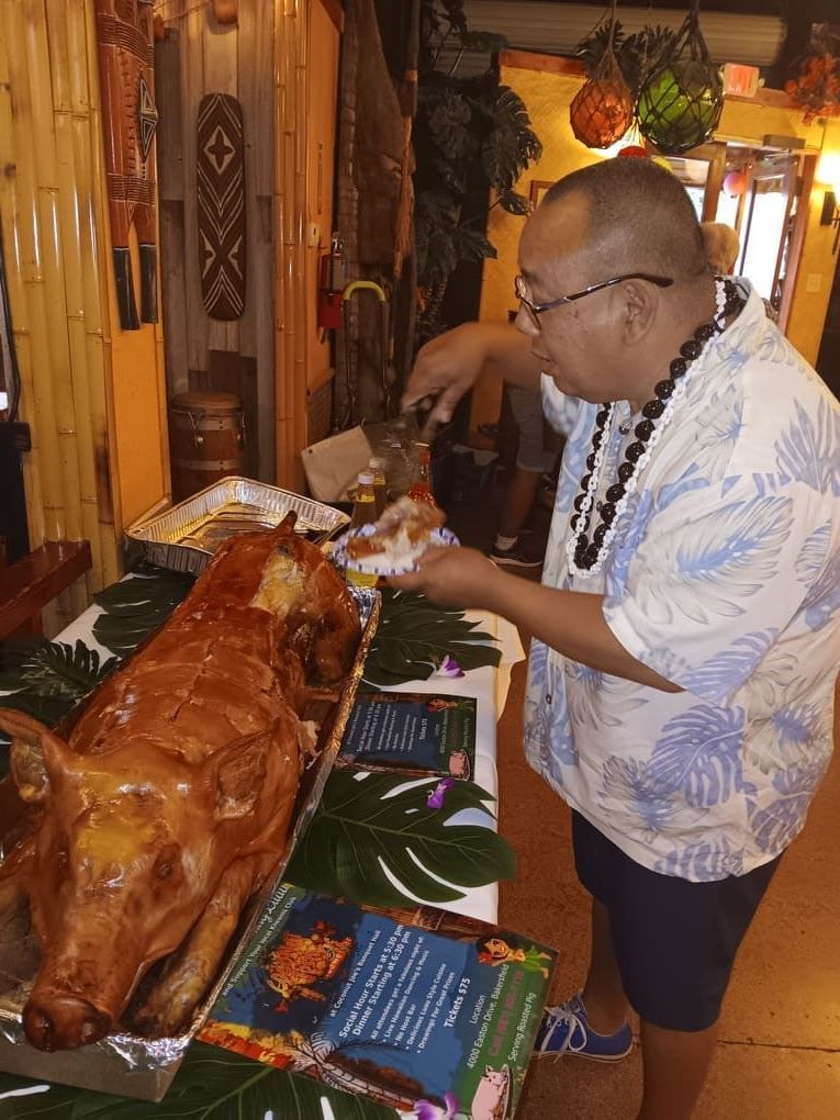 A man is cutting up a whole pig on a table.