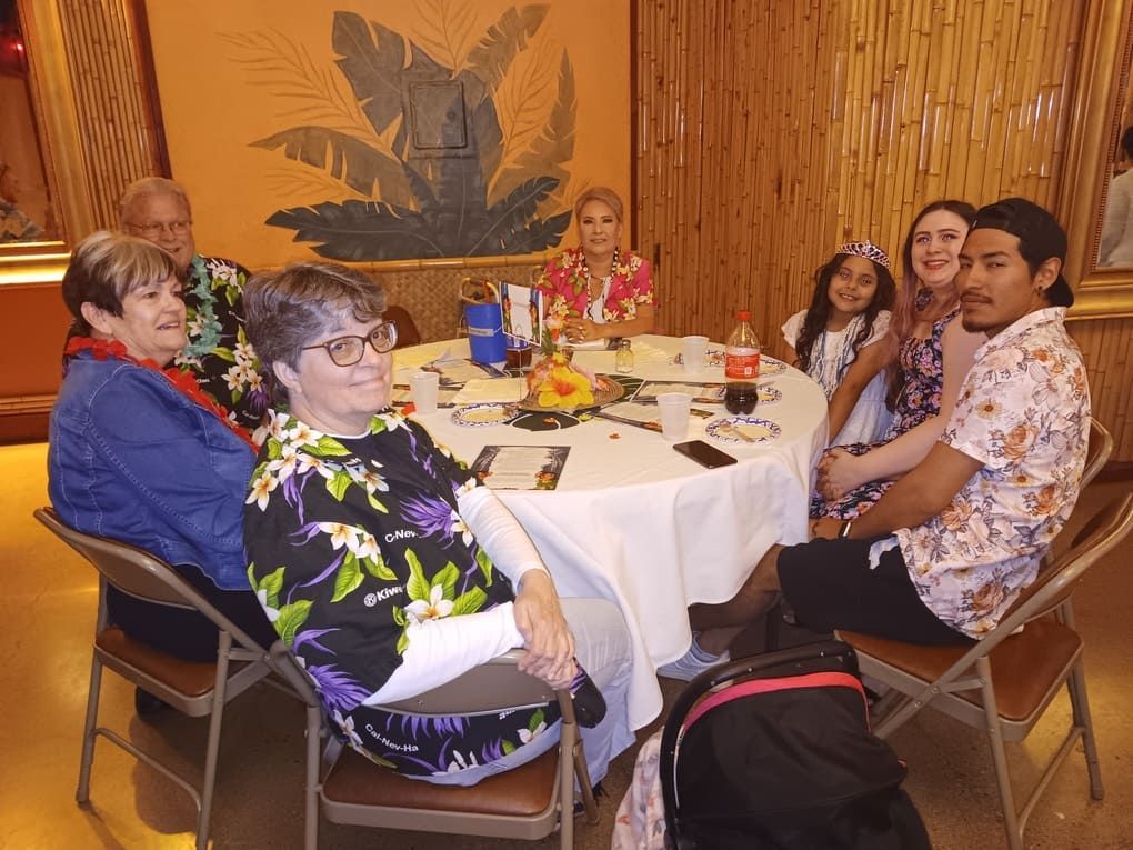 A group of people are sitting around a table with a dog.