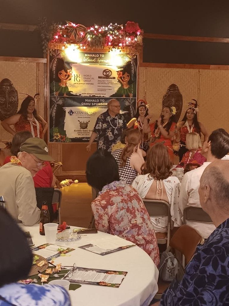 A group of people are sitting at tables in front of a stage.