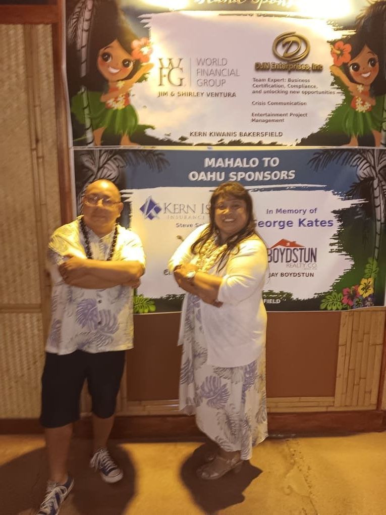 A man and a woman standing in front of a sign that says mahalo to oahu sponsors