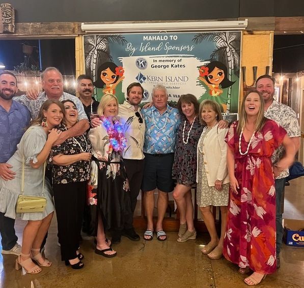 A group of people posing for a picture in front of a sign that says nahalo to