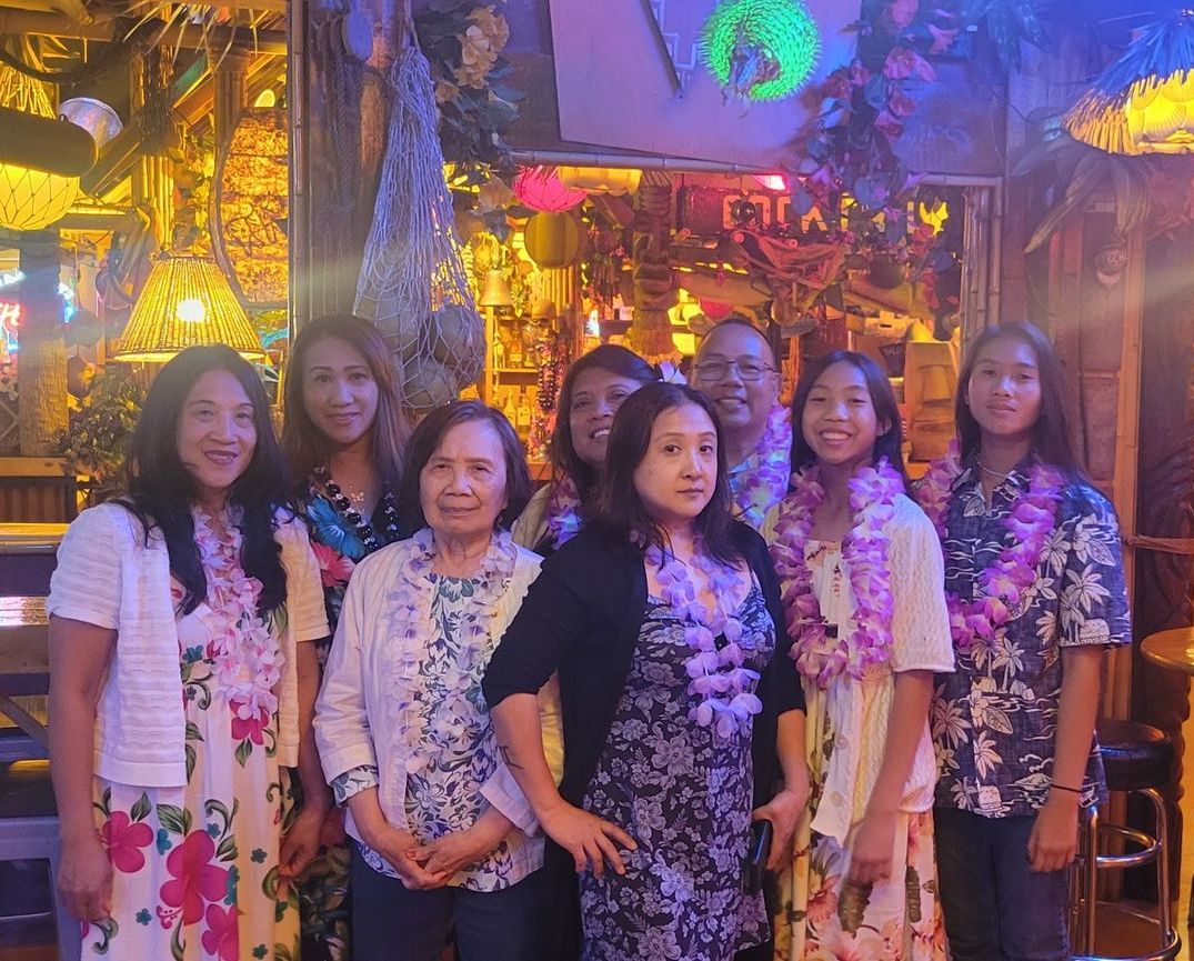 A group of women are posing for a picture in a tiki bar.