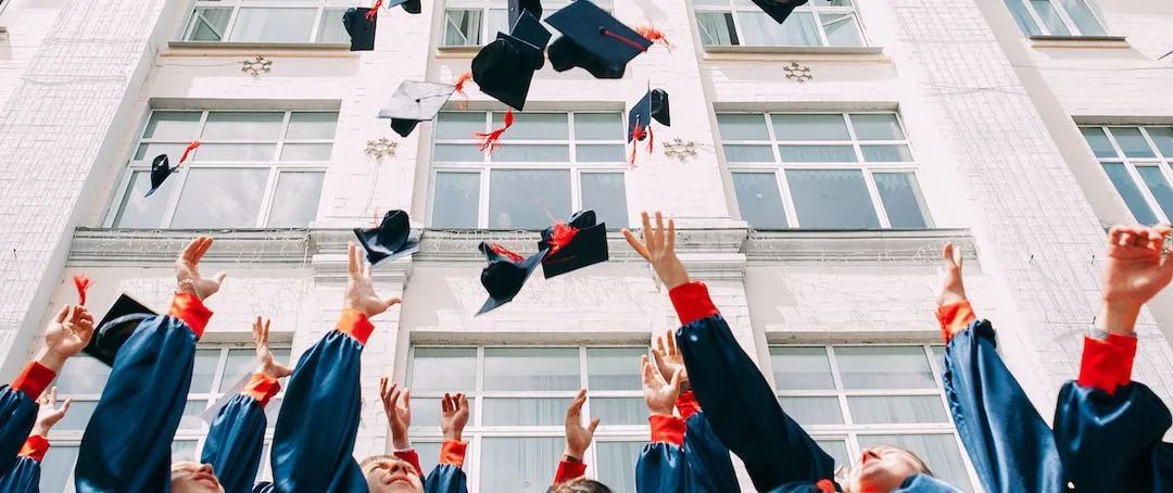 A group of graduates are throwing their caps in the air.