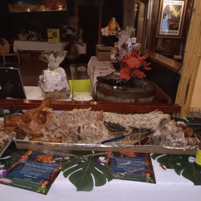 A large, devoured pig is on a tray on a table