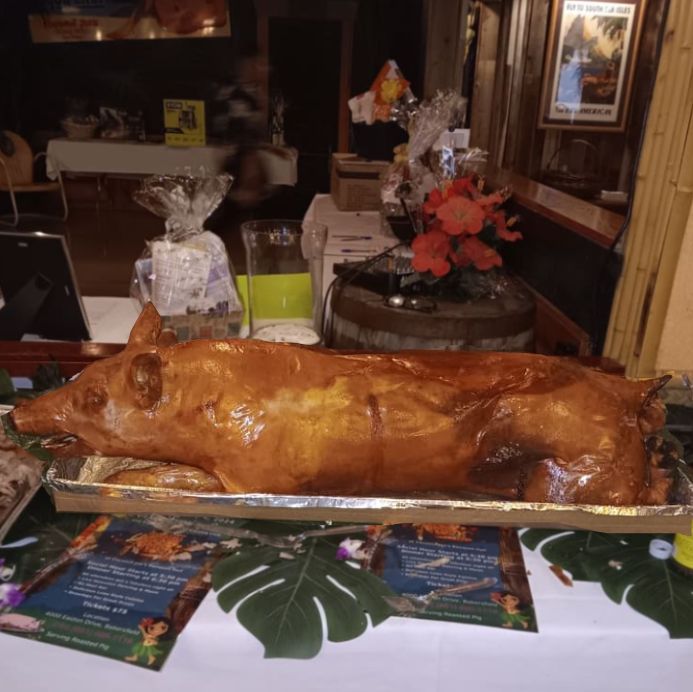 A large roasted pig is on a tray on a table