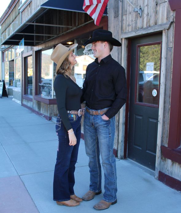 A man and a woman are standing on a sidewalk in front of a building