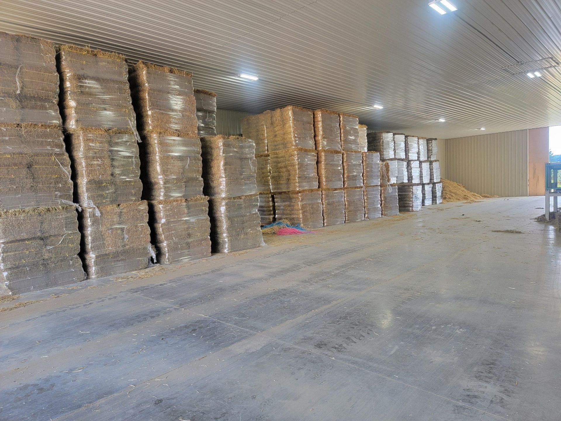 Stacks of wrapped brown blocks inside a large warehouse with a gray floor and ceiling.