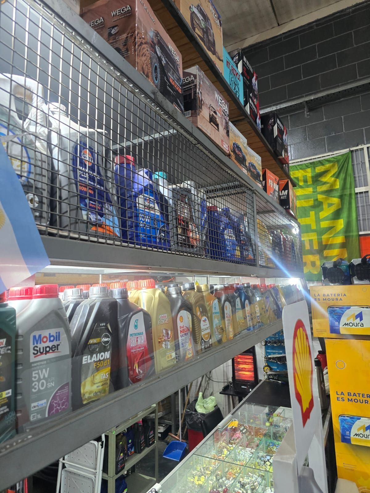 Estantes llenos de varias botellas de aceite de motor en una tienda de repuestos de automóviles.