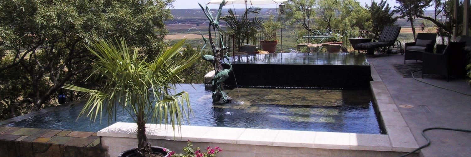 An infinity pool with a view of a green landscape and trees.