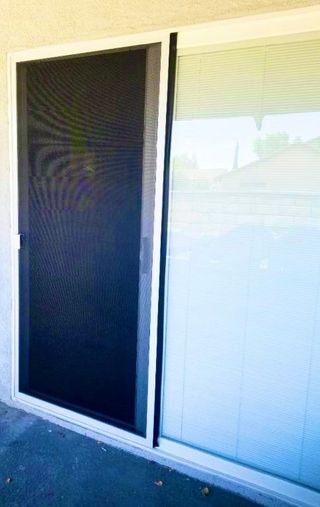 A sliding glass patio door with a black screen door covering the left side.